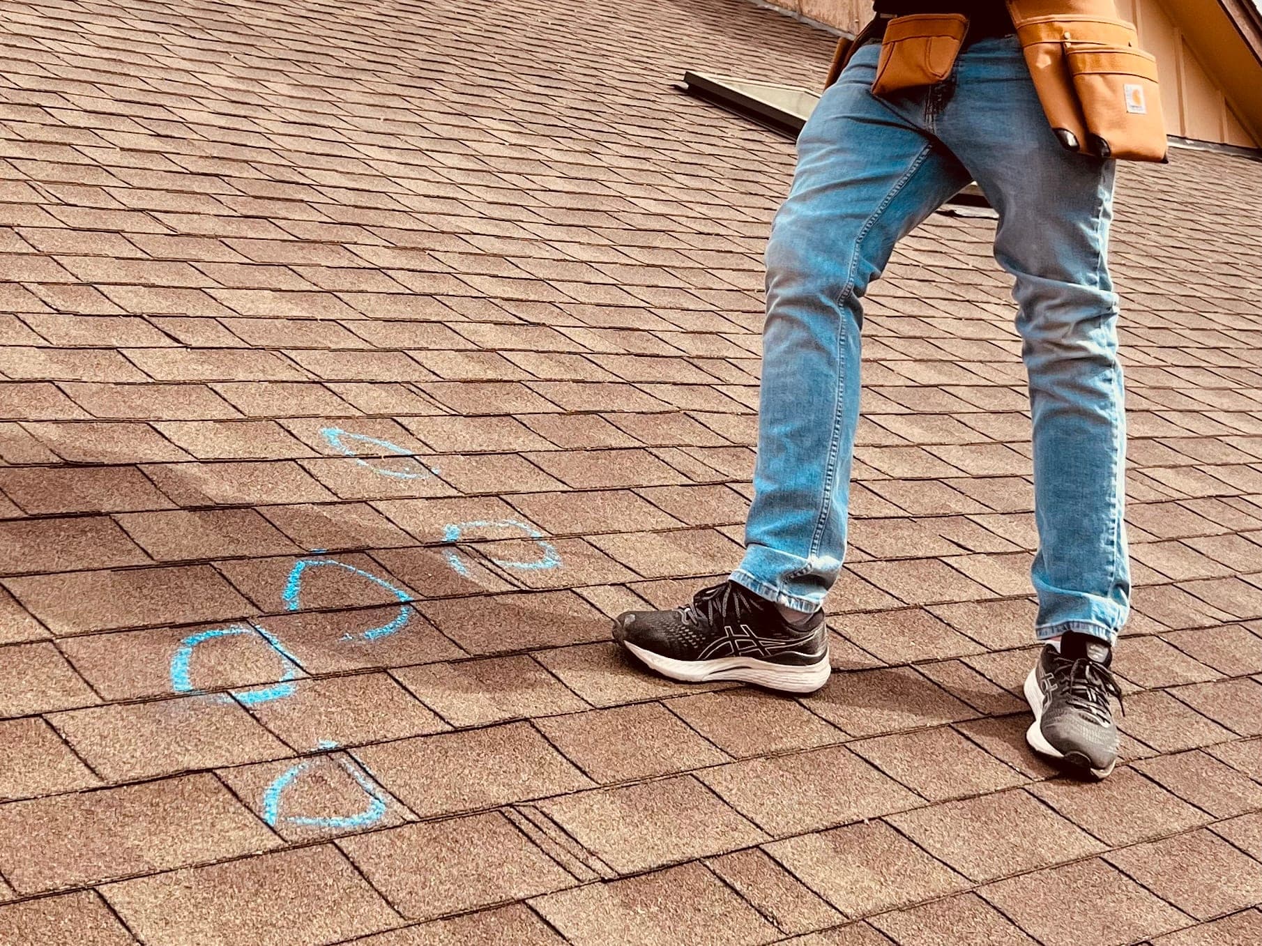 Hail strikes on asphalt shingles circled in blue chalk during a South O Roofing inspection in the Omaha metro