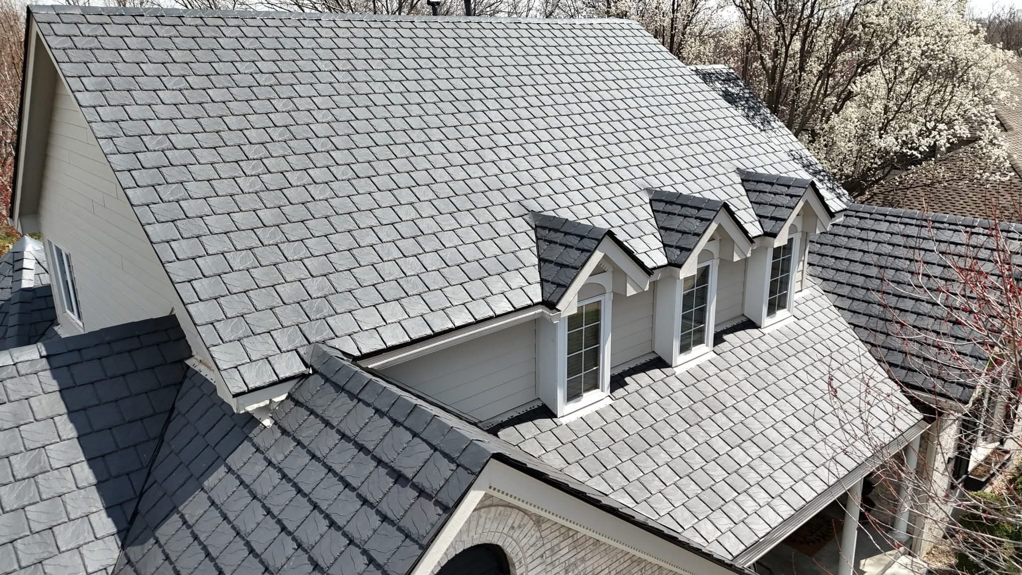 Aerial view of a completed slate-look shingle roof with three dormer windows