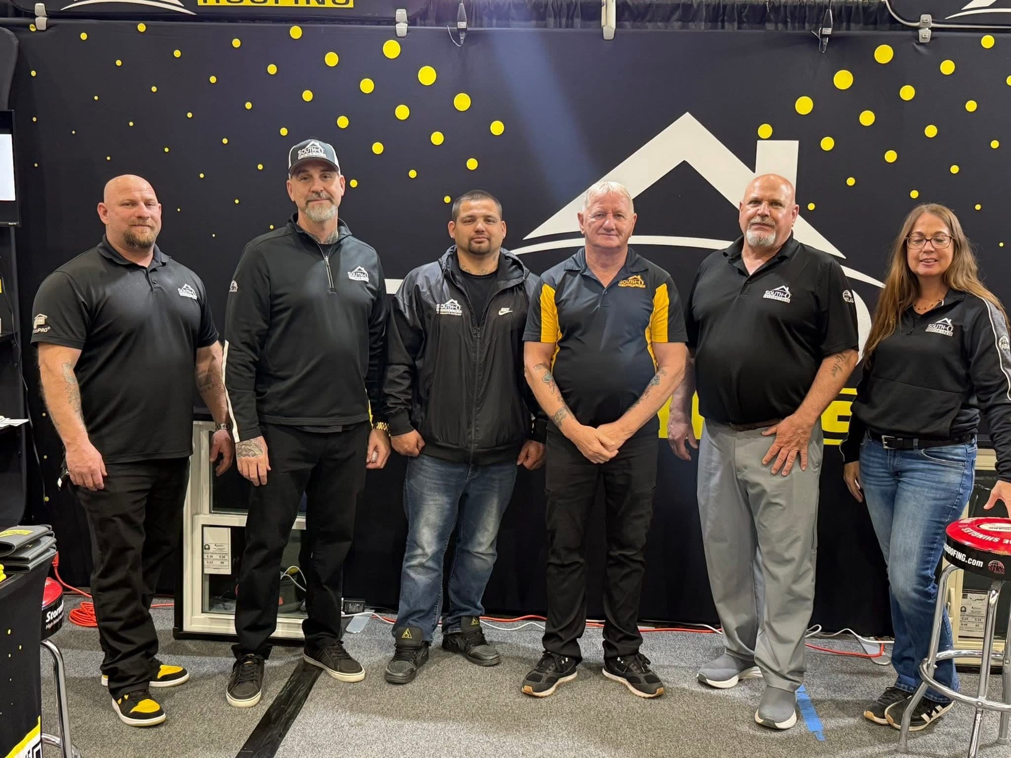 Six South O Roofing team members in branded apparel at the company's trade-show booth